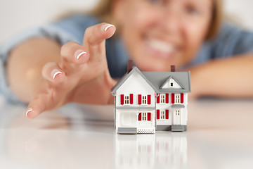 Image showing Smiling Woman Reaching for Model House on White