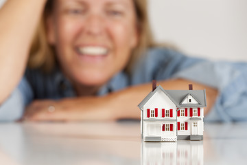 Image showing Smiling Woman Behind Model House on a White Surface