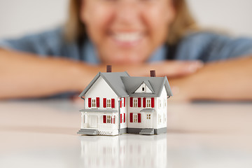 Image showing Smiling Woman Behind Model House on a White Surface