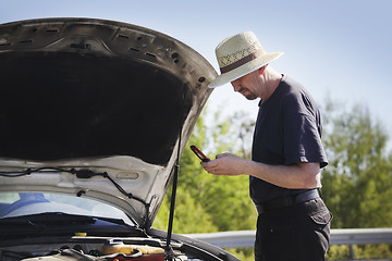 Image showing man on a mobile phone in front of a broken car