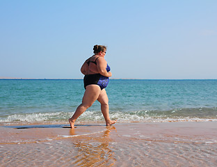Image showing overweight woman running on beach