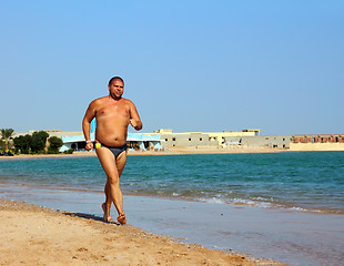 Image showing overweight man running on beach