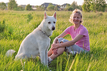 Image showing The woman with a dog sit on a meadow