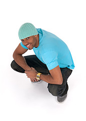 Image showing Smiling young man in a blue t-shirt squatting