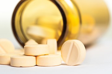 Image showing Pills on whhite floor with bottle in the background