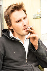 Image showing a homeless poor young guy smoking