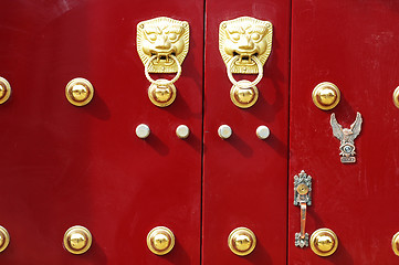 Image showing Red door decorated with golden door knobs