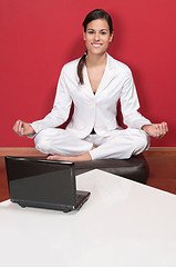 Image showing Smiling businesswoman sitting in yoga lotus position