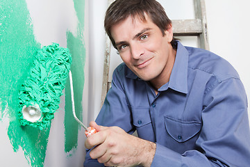 Image showing Mature man painting the wall with a roller