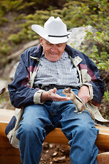 Image showing Elderly man playing with squirrel
