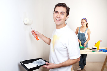 Image showing Smiling man painting the wall of his new apartment