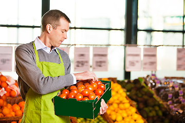 Image showing Market assistant holding box of tomatoes