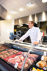 Image showing Cheerful chef on the counter of frozen meat