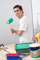 Image showing Casual man holding a roller paint brush