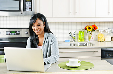 Image showing Woman using computer in kitchen