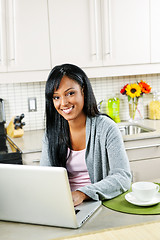Image showing Woman using computer in kitchen
