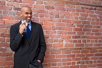 Image showing Young business man drinking wine and smiling