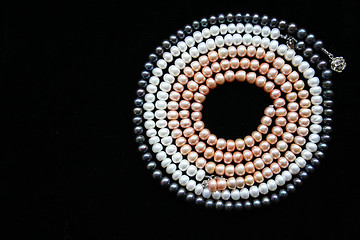 Image showing Circle of white, black and pink pearls on the black background