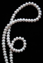 Image showing White pearls on the black silk as background