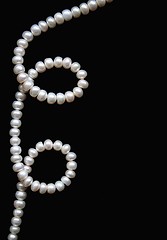 Image showing White pearls on the black silk as background