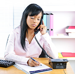 Image showing Serious black businesswoman on phone at desk