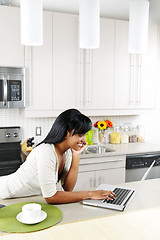 Image showing Woman using computer in kitchen