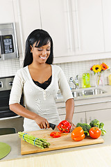 Image showing Young woman cutting vegetables in kitchen