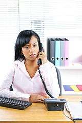 Image showing Concerned black businesswoman on phone at desk