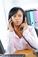 Image showing Black businesswoman using two phones at desk