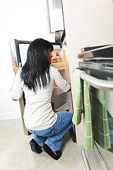 Image showing Young woman looking in refrigerator