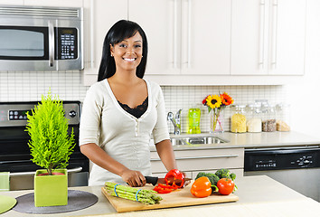 Image showing Young woman cutting vegetables in kitchen