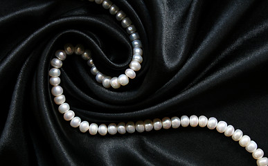 Image showing White pearls on the black silk as background