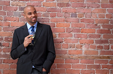 Image showing Smiling young business man drinking wine