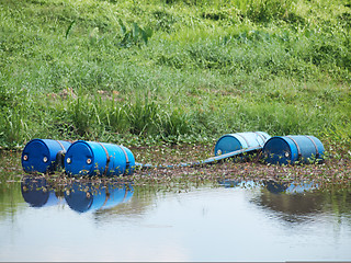 Image showing Blue toxic drums in river