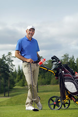 Image showing Man standing by golf bag full of sticks 