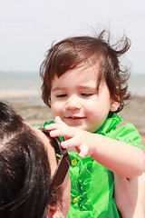 Image showing Baby playing with mother taking her sunglasses