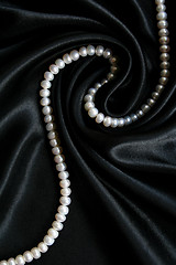 Image showing White pearls on the black silk as background