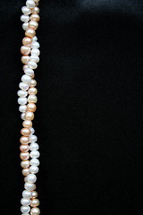 Image showing White and pink pearls on the black silk background