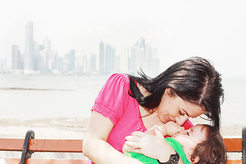 Image showing Mother playing with her baby with the city in the background