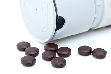 Image showing Some brown pills near pill-dispenser