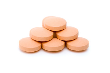 Image showing Few orange tablets lie in form of pyramid