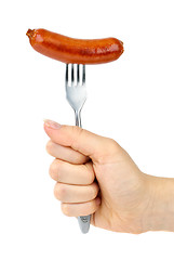 Image showing Hand holding grilled sausage on the fork