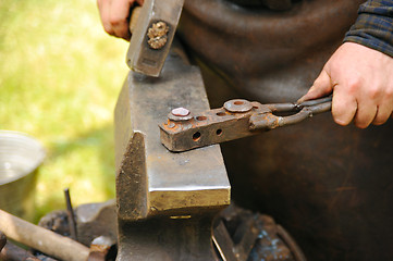 Image showing Blacksmith hammering hot steel on anvil