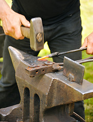 Image showing Blacksmith hammering hot iron on anvil
