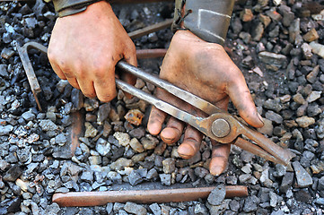 Image showing Detail of dirty hands holding pliers - blacksmith