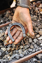 Image showing Detail of dirty hand holding horseshoe - blacksmith