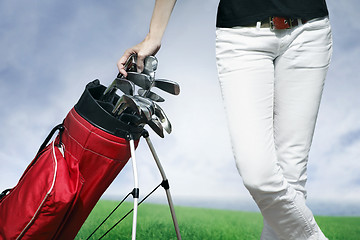 Image showing Women standing by golf bag full of sticks 