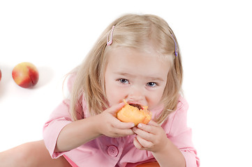 Image showing Little girl eating peach in studio