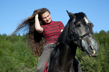 Image showing A girl with flowing hair on a black horse