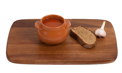 Image showing Soup in clay pot on wooden kitchen board